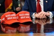 Hats are seen on the desk as President Donald Trump speaks with reporters after signing executive orders in the Oval Office of the White House, Wednesday, April 23, 2025, in Washington. (AP Photo/Alex Brandon)