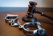 Gavel and handcuffs sit on a leather surface